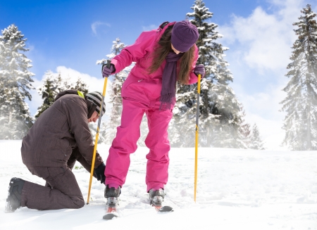 
young man helps her girlfriend to put her skis on winter backgroundの写真素材