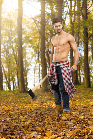 Young woodcutter with axe in forestの写真素材