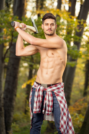 Young handsome man working with axe in forest の写真素材