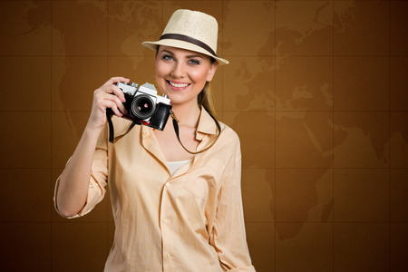 smiling female tourist holding photo camera with map world in backgroundの写真素材