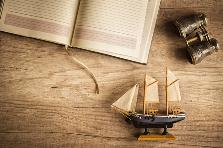 Wooden table with antique travelling stuff, compass, map, vintage binoculars, photo cameraの写真素材
