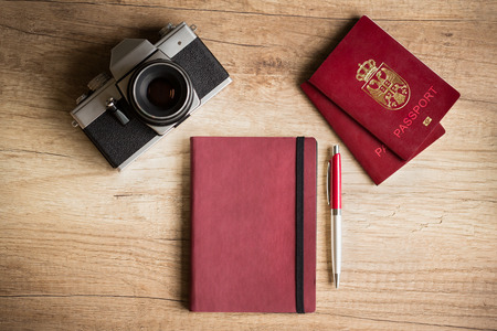 Photo camera and passport on wooden deskの写真素材