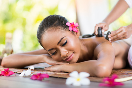 young woman receiving massage of back with stone massageの写真素材