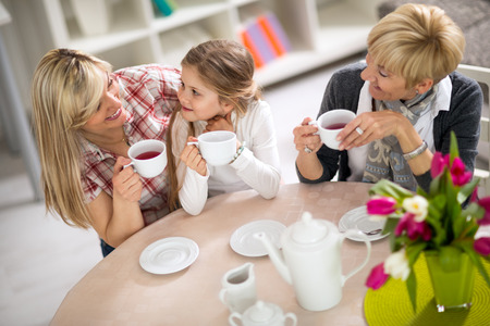 Mom and daughter on a visit to with her grandmother, three generations together drinking teaの写真素材