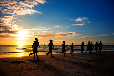 group of young people runs at the beach on beautiful summerの写真素材