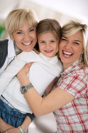 Smiling grandmother and mother embracing little girl,  proud of her