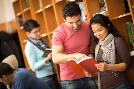 Couple of studying  friends reading book from library
