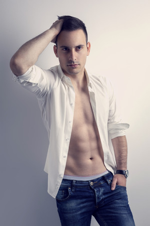 Sexy man with unbuttoned shirt leaning against the wallの写真素材