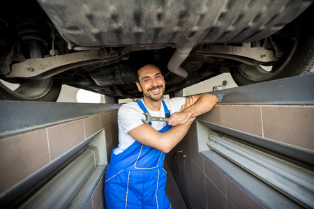 smiling mechanic underneath a carの写真素材