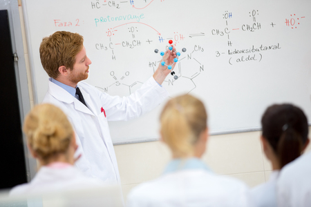 Young male chemistry teacher show molecular model to students in classroomの写真素材