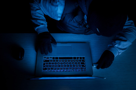 Hacker thief with laptop in darknessの写真素材