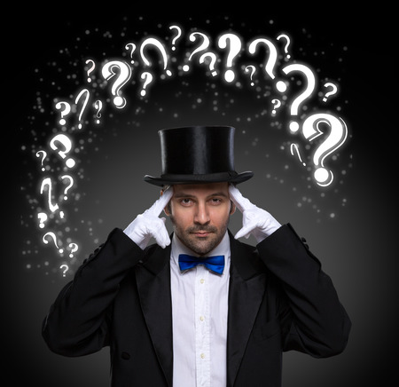 thinking magician surrounded by question marksの写真素材