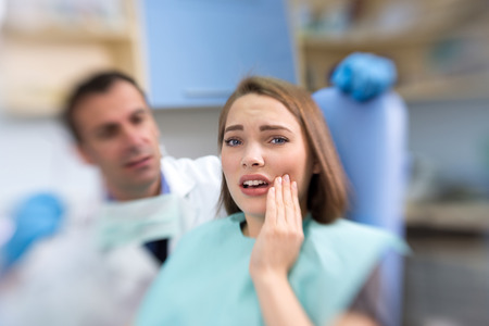 Close up of young female patient with toothache and pain in dental clinicの写真素材