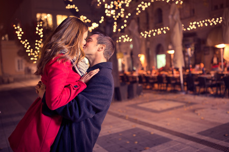 Young affectionate couple kissing tenderly on Christmas street Young affectionate couple kissing tenderly on Christmas street