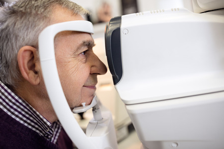 Close up of senior check his sight using apparatus at eye clinic