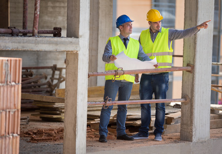Two male architects show building place and discus with colleaguearchitect, male