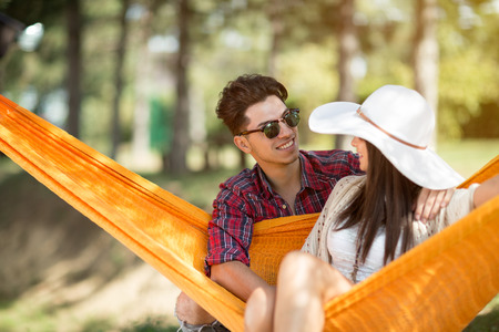 Young guy hugging nice girl in orange hammock in forestの写真素材