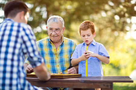 Grandfather and grandson are playing chess in park