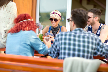 Guys and lassies in nice spring day in restaurant outdoor play cards, drinks beer and makes jokeの写真素材