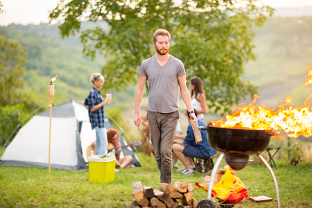 Man put firewood in flared up grill in natureの写真素材