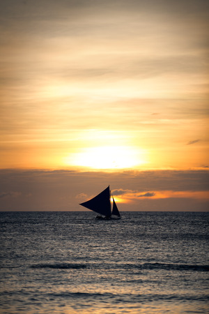 Beautiful gold sunset with a sailboat sailingの写真素材