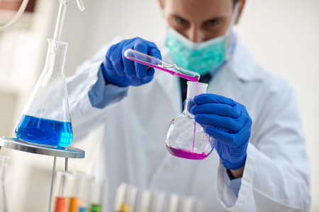 scientist with pipette and flask making test or research in clinical laboratory
