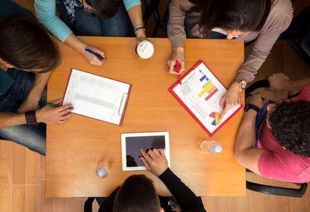 Top view of working table with students, tablet and statistics in teamworkの写真素材