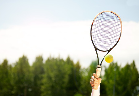 Close up of raised tennis racket and ball