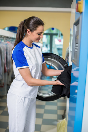 Employees putting clothes in the dryer in dry cleanerの写真素材