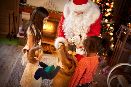 Little girls receiving Christmas presents from real Santa Clausの写真素材