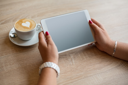 top view coffee cup and tablet in female hands in cafe