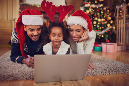 Christmas afro African young cheerful family using laptop, spending Christmas time togetherの写真素材