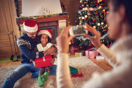 Mother making photo with smart phone of daddy and little daughterの写真素材