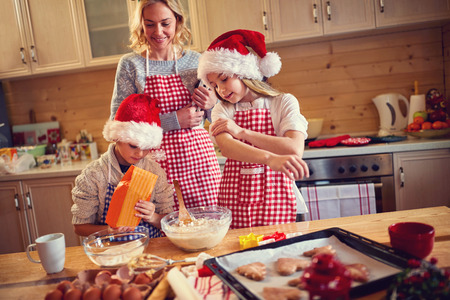 Family of children and mother baking cookies at home on Xmas eve