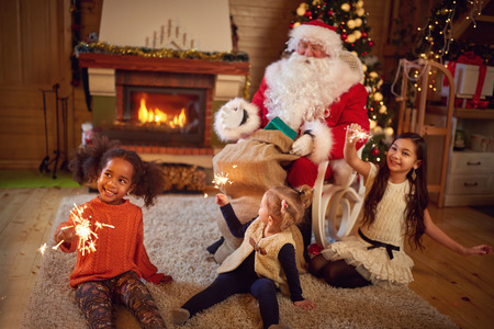 Three girls playing with Christmas sprinklers with Santa Claus in Christmas atmosphereの写真素材