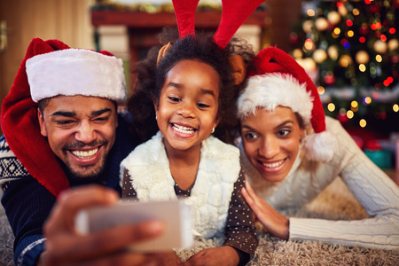 smiling mother, father and daughter - Christmas selfieの写真素材