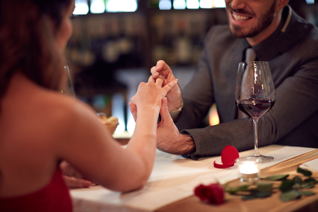 Man put ring on girlfriends finger in restaurantの写真素材