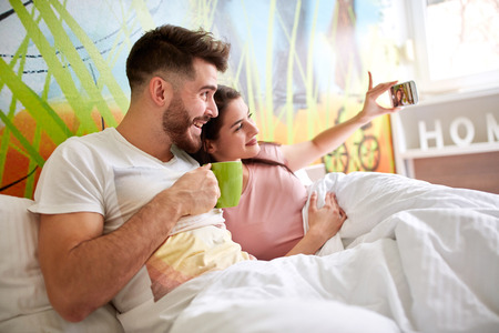 Couple making selfie together in bedの写真素材