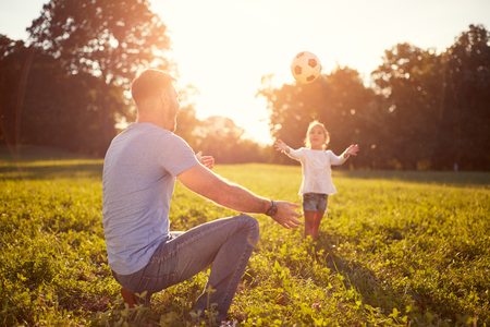 Young father playing ball with daughter outdoorの写真素材