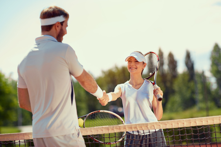 Young player and couch shaking hands after tennis trainingの写真素材