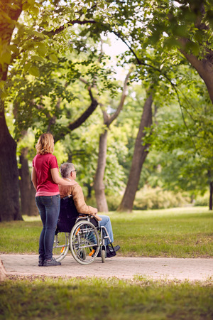 enjoying together senior man in wheelchair and daughter in the parkの写真素材
