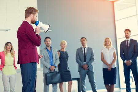 leader with megaphone talking his business team of successful dealingの写真素材