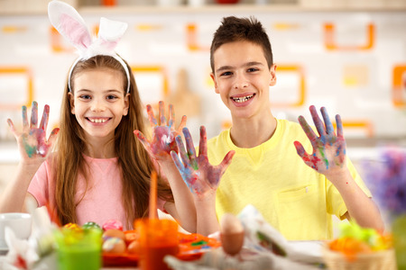 Smiling boy and girl show painting hands with eggs colorの写真素材
