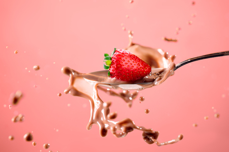 Strawberry splash in milk isolated on red backgroundの写真素材