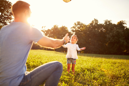 Girl with father plays ball on summer in parkの写真素材