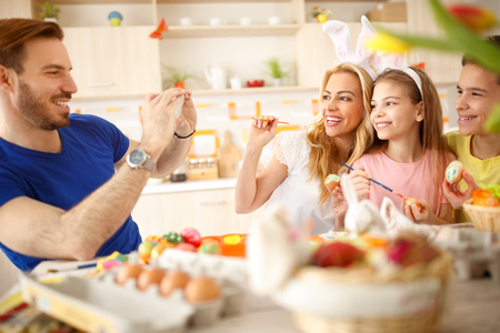 Father taking family photo on cell phone for memory on Easter festivityの写真素材