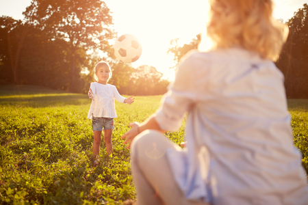 Child play with ball with mother on summer in parkの写真素材
