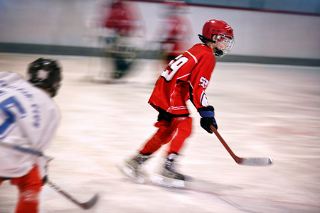 young boy playing ice hockey on the rinkの写真素材