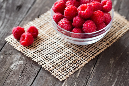 Sweet fresh raspberry in bowl on wood background