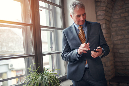 freelance senior businessman in suit with smartphone workingの写真素材